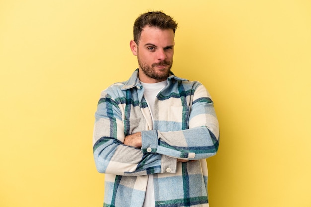 Young caucasian man isolated on yellow background unhappy looking in camera with sarcastic expression.