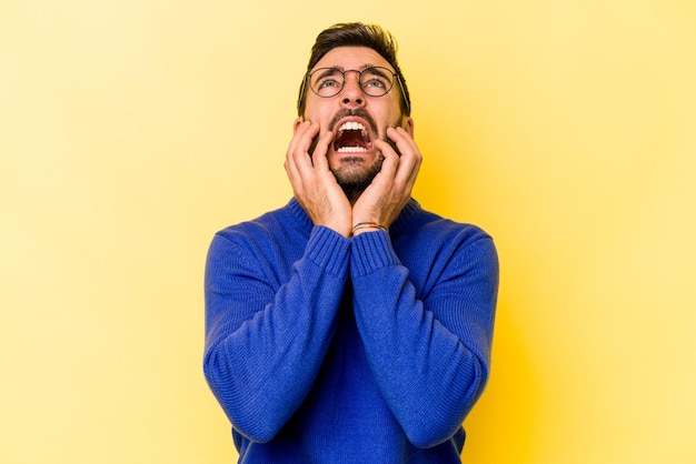 Young caucasian man isolated on yellow background whining and crying disconsolately