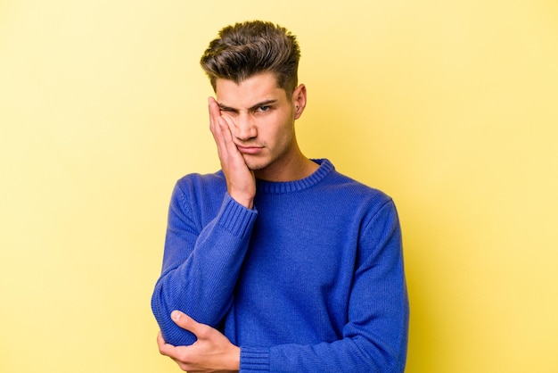 Young caucasian man isolated on yellow background who is bored, fatigued and need a relax day.