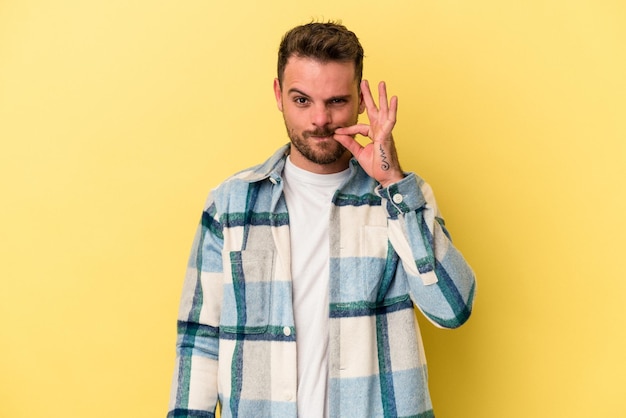 Young caucasian man isolated on yellow background with fingers on lips keeping a secret.