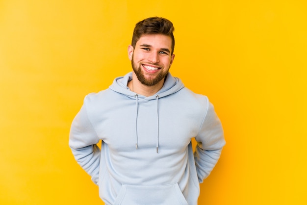 Young caucasian man isolated on yellow happy, smiling and cheerful.