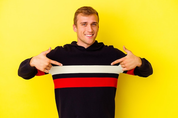 Young caucasian man isolated on yellow points down with fingers, positive feeling.