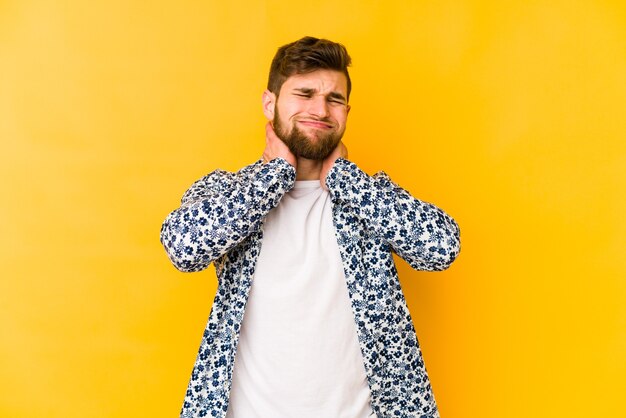 Young caucasian man isolated on yellow suffering neck pain due to sedentary lifestyle.