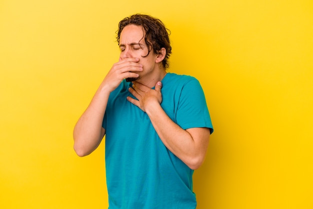 Il giovane uomo caucasico isolato su giallo soffre di dolore alla gola a causa di un virus o di un'infezione.