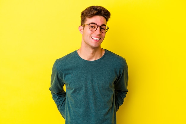 Young caucasian man isolated on yellow wall happy, smiling and cheerful.