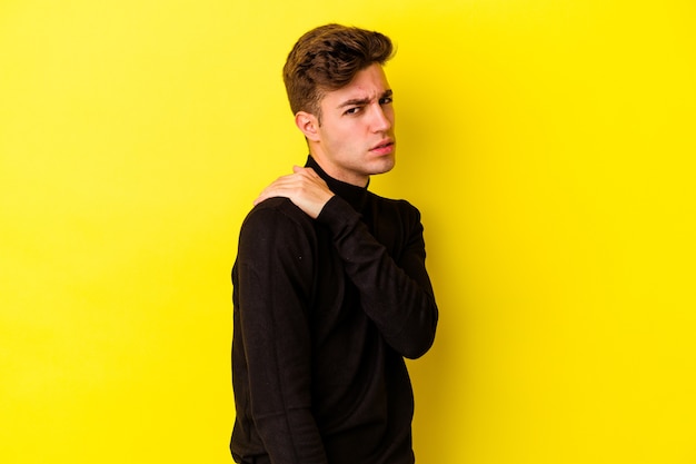 Young caucasian man isolated on yellow wall having a shoulder pain.