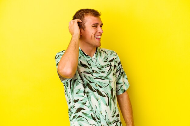 Young caucasian man isolated on yellow wall joyful laughing a lot. Happiness concept.