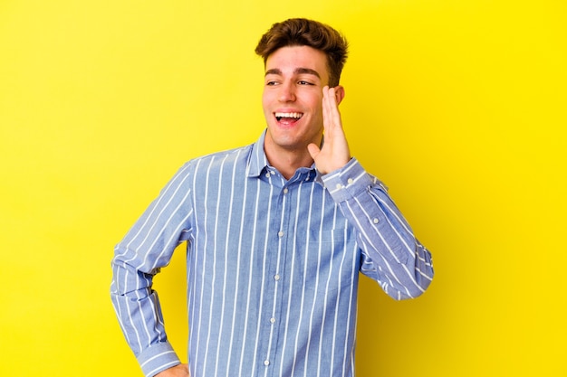 Young caucasian man isolated on yellow wall shouting excited to front.