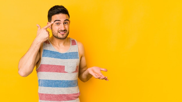 Young caucasian man isolated on yellow wall showing a disappointment gesture with forefinger.
