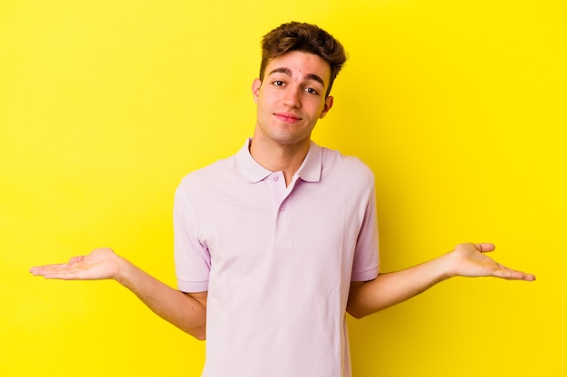 Young caucasian man isolated on yellow wall showing a welcome expression