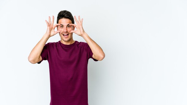 Giovane uomo caucasico tenendo gli occhi aperti per trovare un'opportunità di successo.