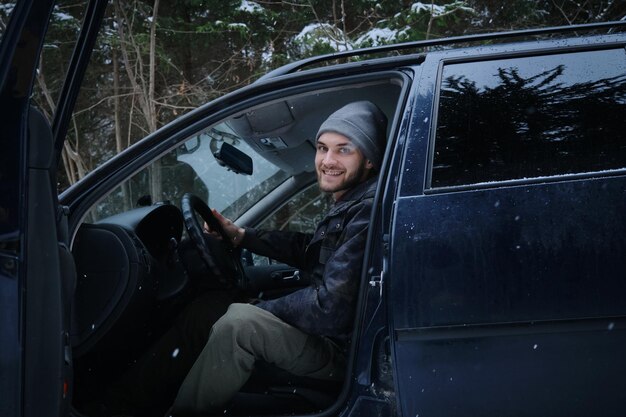 冬に険しい道路で車の運転を学ぶ白人の若い男性