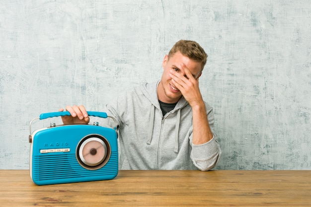 Молодой человек кавказской, слушая радио моргать сквозь пальцы