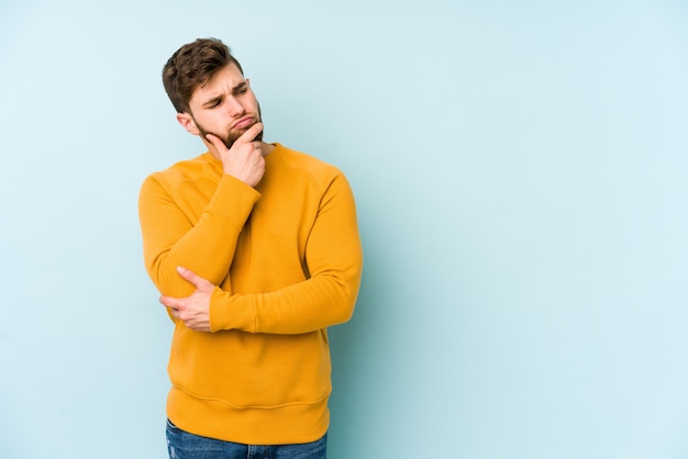 Young caucasian man looking sideways with doubtful and skeptical expression.