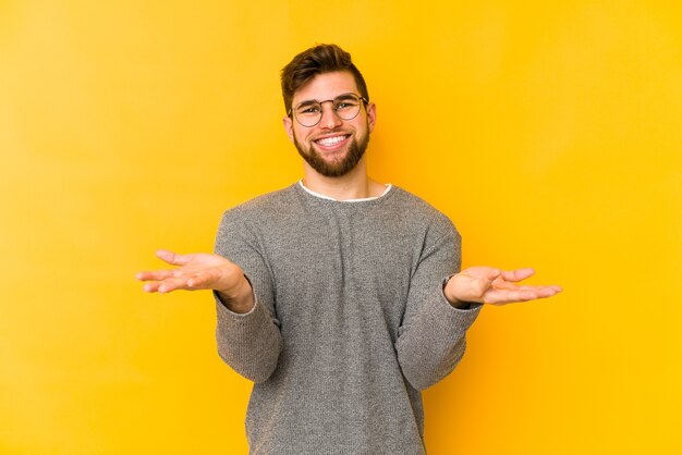 Young caucasian man makes scale with arms, feels happy and confident.