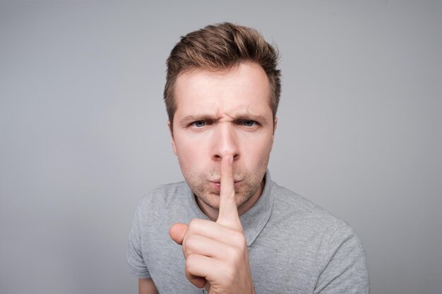 Young caucasian man making silence gesture