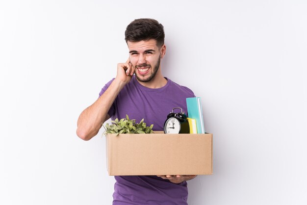 Young caucasian man moving a new home isolated covering ears with hands.