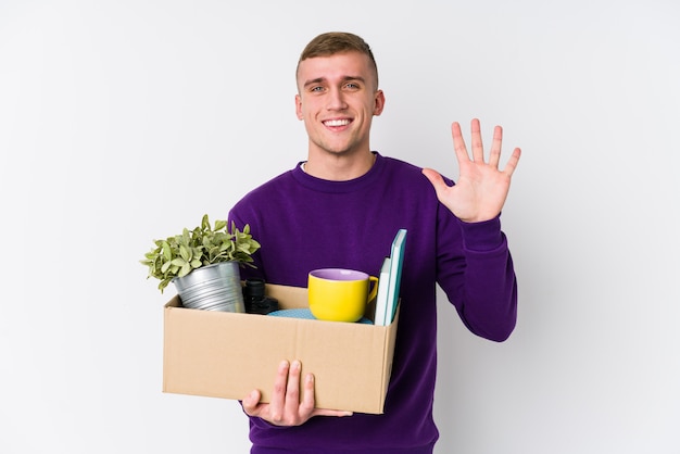 Young caucasian man moving to a new home smiling cheerful showing number five with fingers.