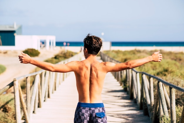 Foto giovane uomo caucasico a braccia aperte godendosi la spiaggia durante le vacanze estive summer