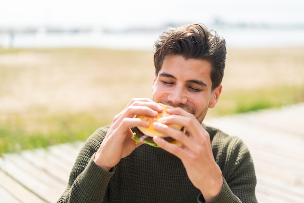 ハンバーガーを持って屋外で若い白人男