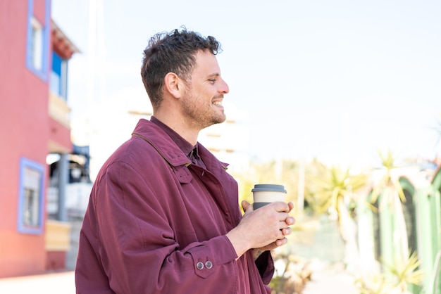 Young caucasian man at outdoors holding a take away coffee