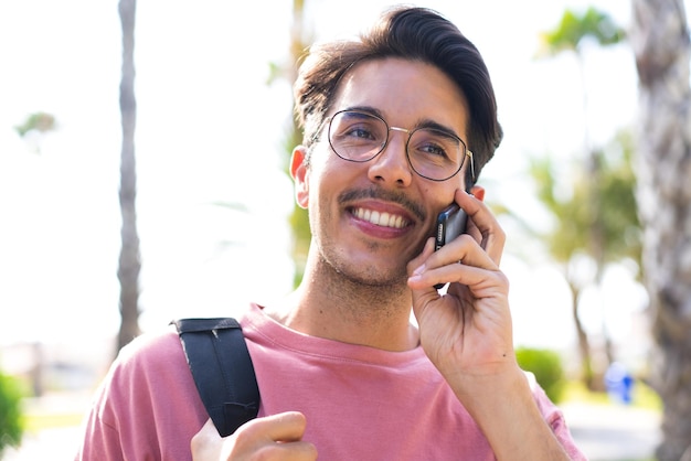 행복 한 표정으로 휴대 전화를 사용 하 여 공원에서 야외에서 젊은 백인 남자