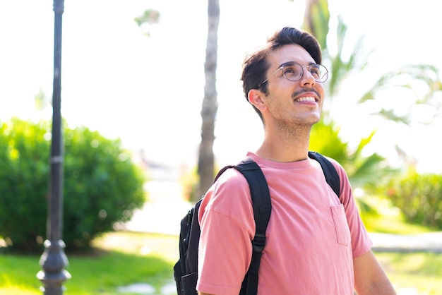 Молодой кавказский человек на открытом воздухе в парке со счастливым выражением лица
