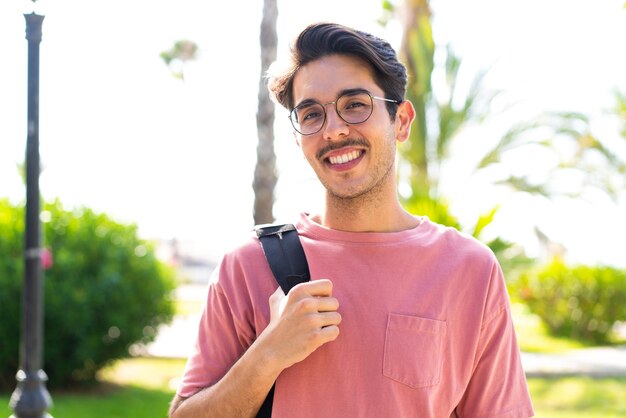 Young caucasian man at outdoors in a park with happy expression