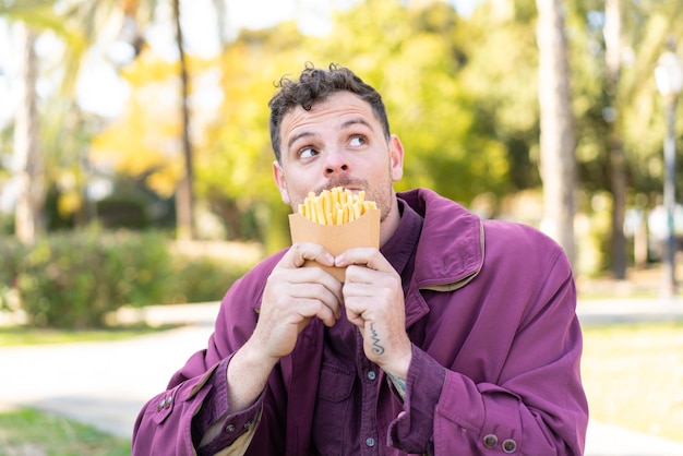 Young caucasian man at outdoors taking fried chips