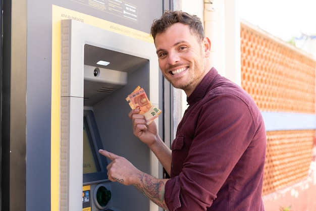 young caucasian man at outdoors using an atm