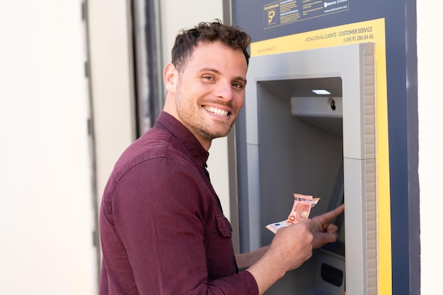 Young caucasian man at outdoors using an ATM