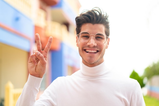 Young caucasian man at outdoors With glasses and doing OK sign