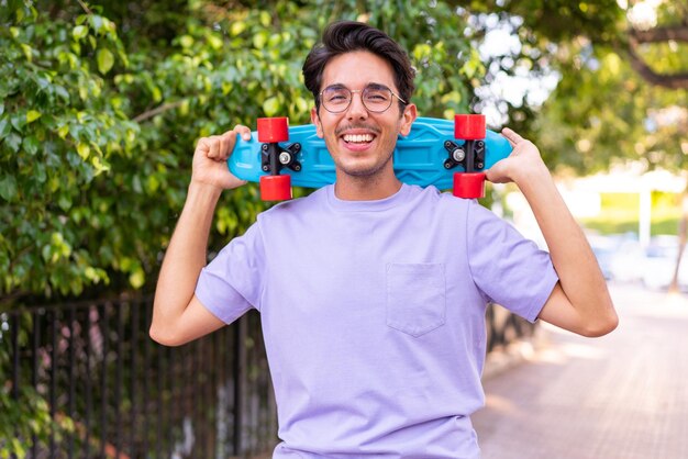 Young caucasian man in a park with a skate