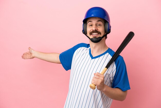 Young caucasian man playing baseball isolated on pink background extending hands to the side for inviting to come