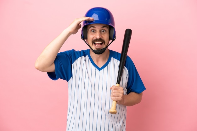 Young caucasian man playing baseball isolated on pink background with surprise expression