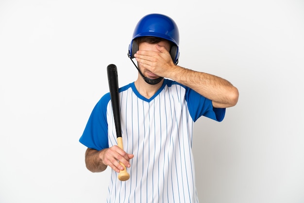 Young caucasian man playing baseball isolated on white background covering eyes by hands. Do not want to see something