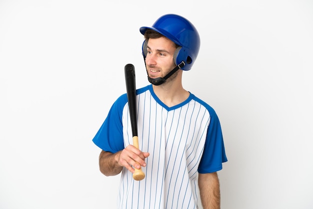 Young caucasian man playing baseball isolated on white background looking to the side and smiling