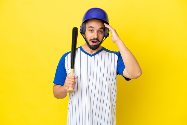 Young caucasian man playing baseball isolated on yellow background with surprise expression