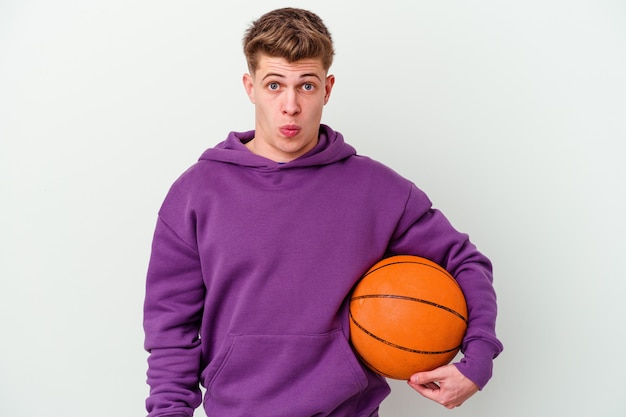 Young caucasian man playing basketball isolated wall shrugs shoulders and open eyes confused.
