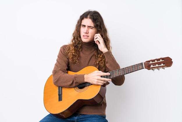 Young caucasian man playing guitar isolated covering ears with hands.