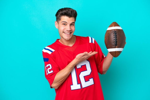 Young caucasian man playing rugby isolated on blue background\
extending hands to the side for inviting to come