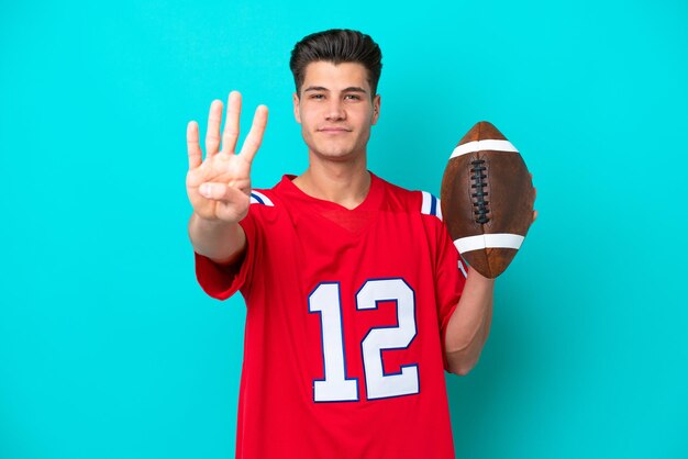 Young Caucasian man Playing rugby isolated on blue background happy and counting four with fingers