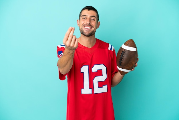 Young caucasian man playing rugby isolated on blue background making money gesture