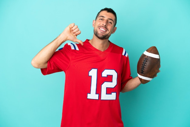 Young caucasian man playing rugby isolated on blue background proud and self-satisfied