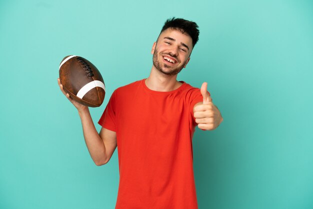 Young Caucasian man playing rugby isolated on blue background with thumbs up because something good has happened