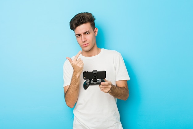 Young caucasian man playing videogames with phone