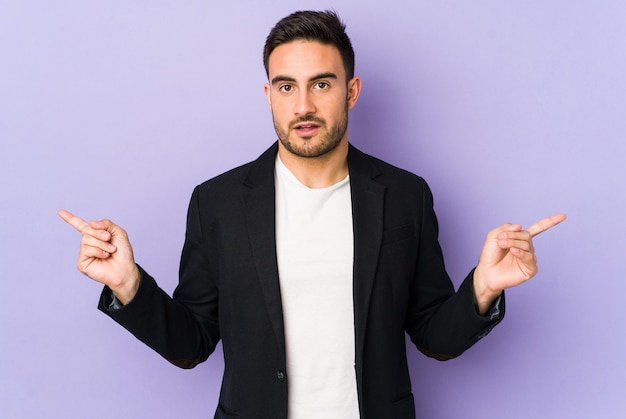 Young caucasian man pointing to different copy spaces, choosing one of them, showing with finger.