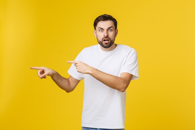 Young caucasian man pointing at something interesting on a yellow.