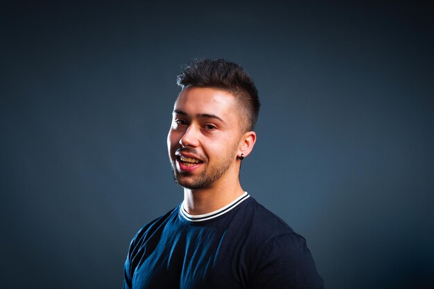 Young caucasian man portrait in a photography studio with a blue background.