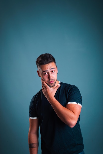 Young caucasian man portrait in a photography studio with a blue background.